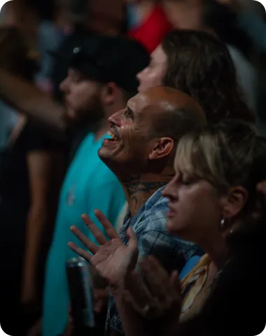 Audience members standing and smiling during a worship or celebration event.