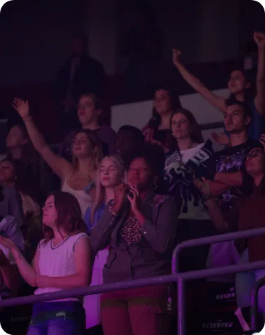 Audience cheering and clapping during a Dream Center event in a large indoor space.